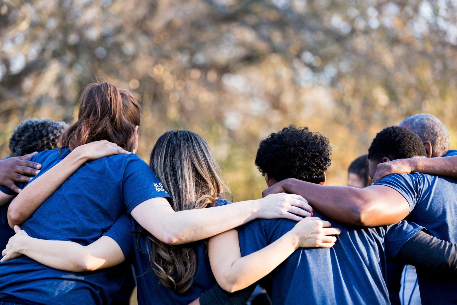 Team huddled together outdoors, arms around each other