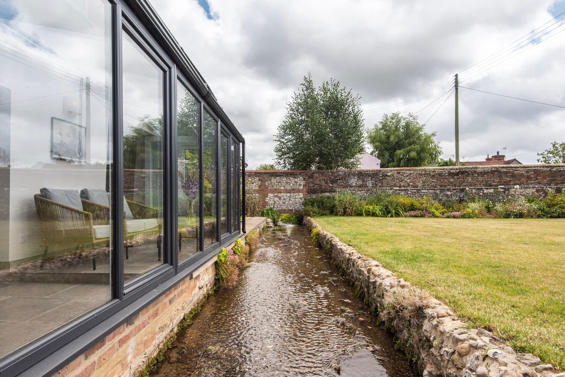 The creek running past the glazed wall of the house