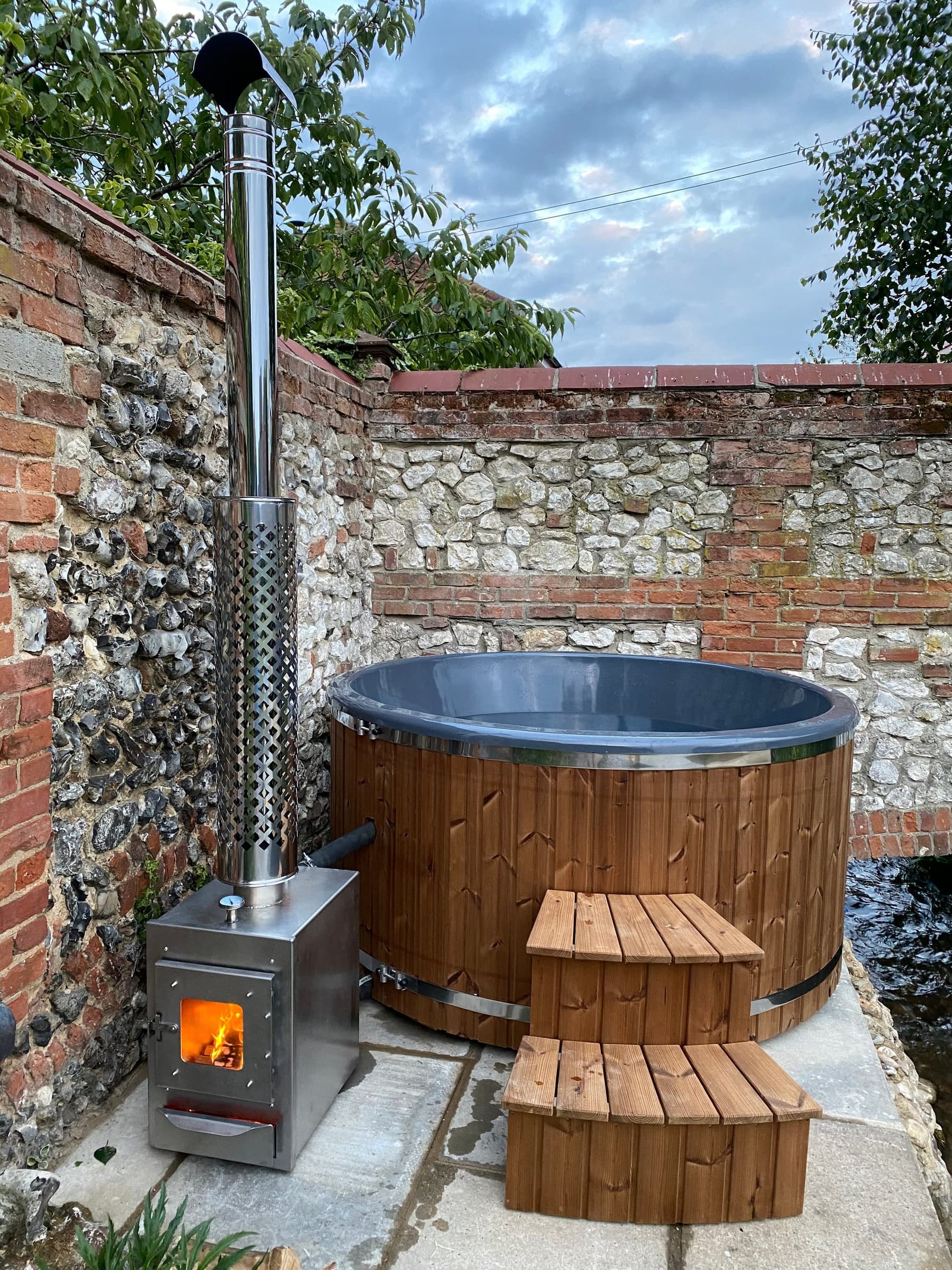 The wood-fired hot tub against the flint wall at South Creek Retreat